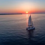 Golden sunset light on the caldera rim viewed from a catamaran during a Santorini sunset boat tour, Greece